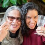 Two joyful women enjoying a friendship toast outdoors with wine glasses in Portugal.